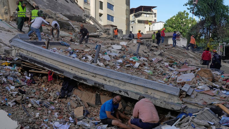 Residentes y rescatistas buscan entre los escombros de un edificio que se derrumbó en los...