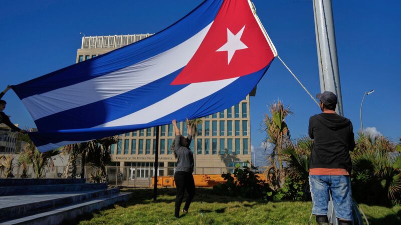 Trabajadores colocan la bandera cubana a media asta en la Tribuna Antiimperialista, cerca de...