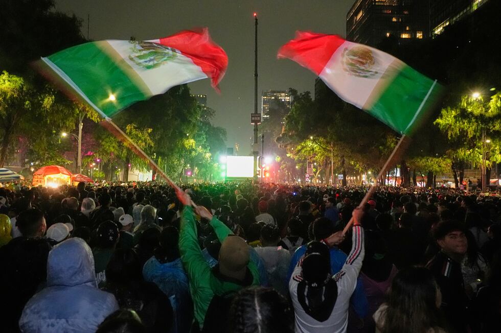 Mexican fans wave flags as they watch the World Cup round of 32 soccer match between Mexico...
