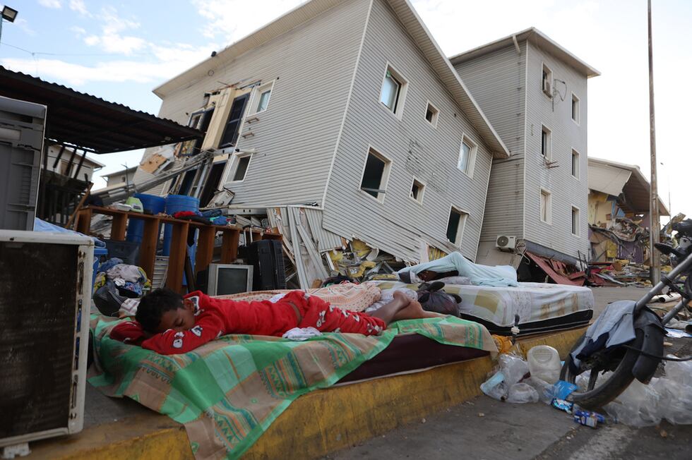 Un niño duerme a la intemperie, frente a casas dañadas por el terremoto en Catia La Mar,...