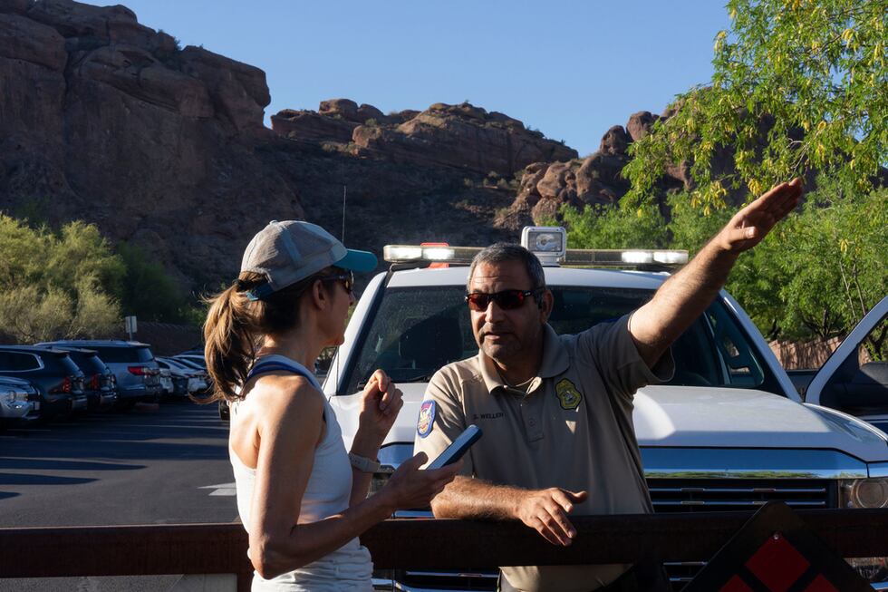 Un guardaparques le da instrucciones a una excursionista debido al calor extremo en Camelback...