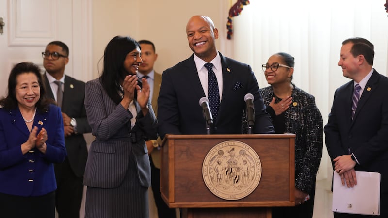 El gobernador de Maryland Wes Moore, centro, sonríe antes de firmar una legislación que...