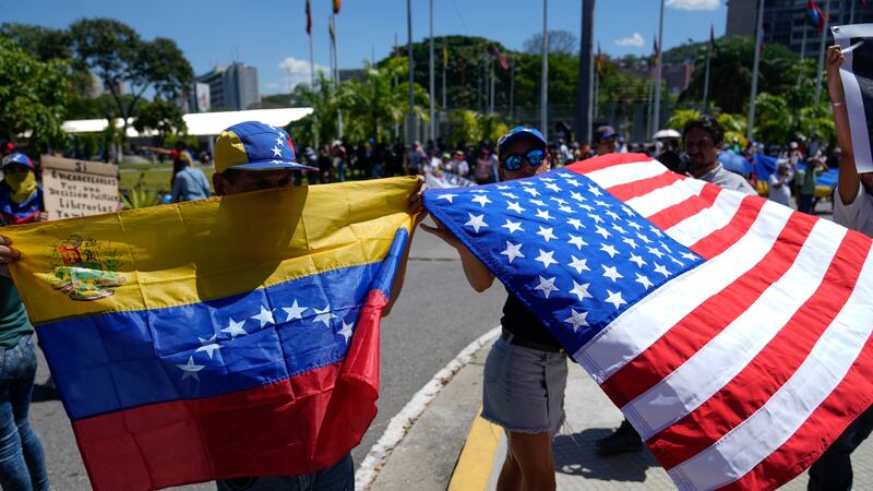 Demonstrators hold a Venezuelan and U.S. national flags during a student-led march calling for...