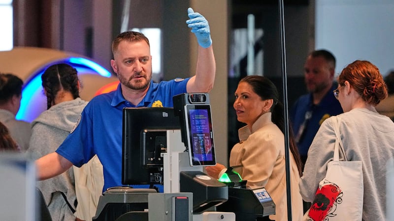 Un agente de la TSA revisa a los pasajeros en el control de seguridad del Aeropuerto...